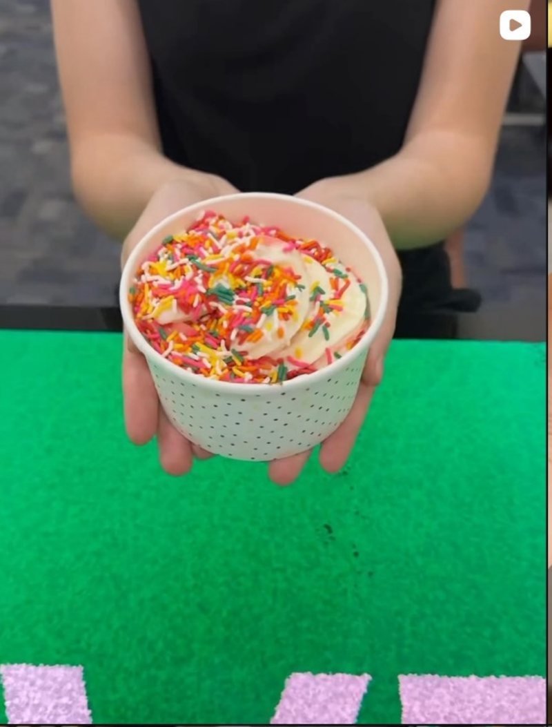 A cup of self-serve frozen yogurt topped with colorful sprinkles