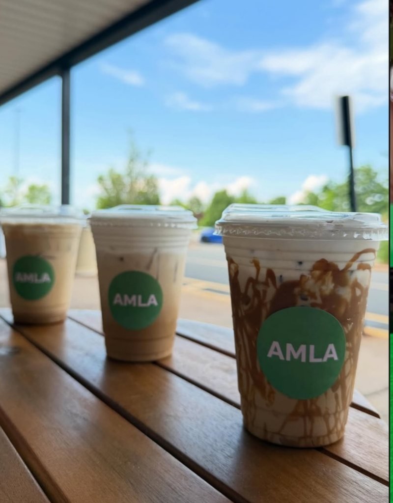 Three AMLA iced drinks lined up on a wooden table by the window
