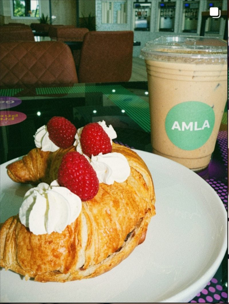 A fresh pastry topped with strawberries and cream, served with an iced latte