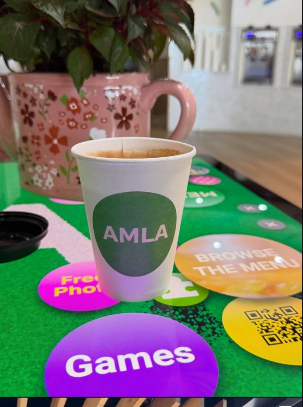 An AMLA coffee cup on one of the cafe's interactive touchscreen tables, with on-screen Games and Browse the Menu buttons